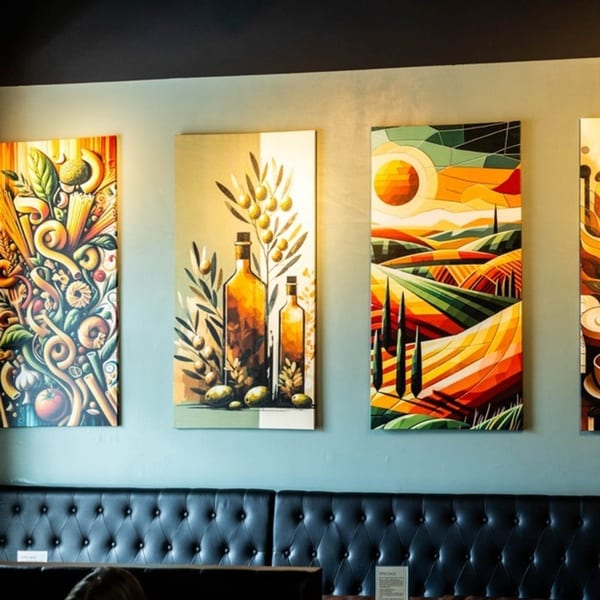 Colorful Italian-themed art, including pasta, olive oil, and a Tuscan landscape, hangs above black leather booths.